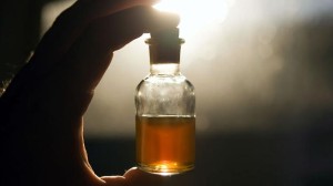 Man holds small glass bottle of liquid in hand